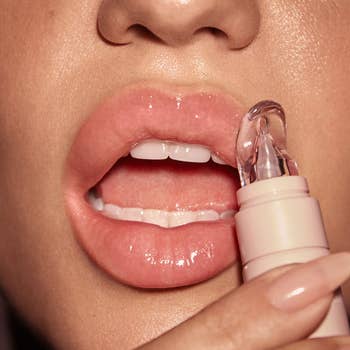 Close-up of a person applying clear lip gloss to their lips