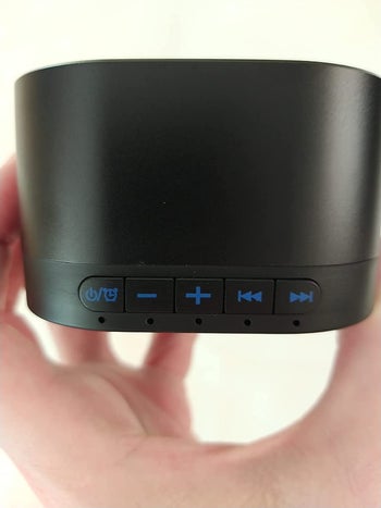 close up of the same reviewer holding the noise machine, showing the different buttons