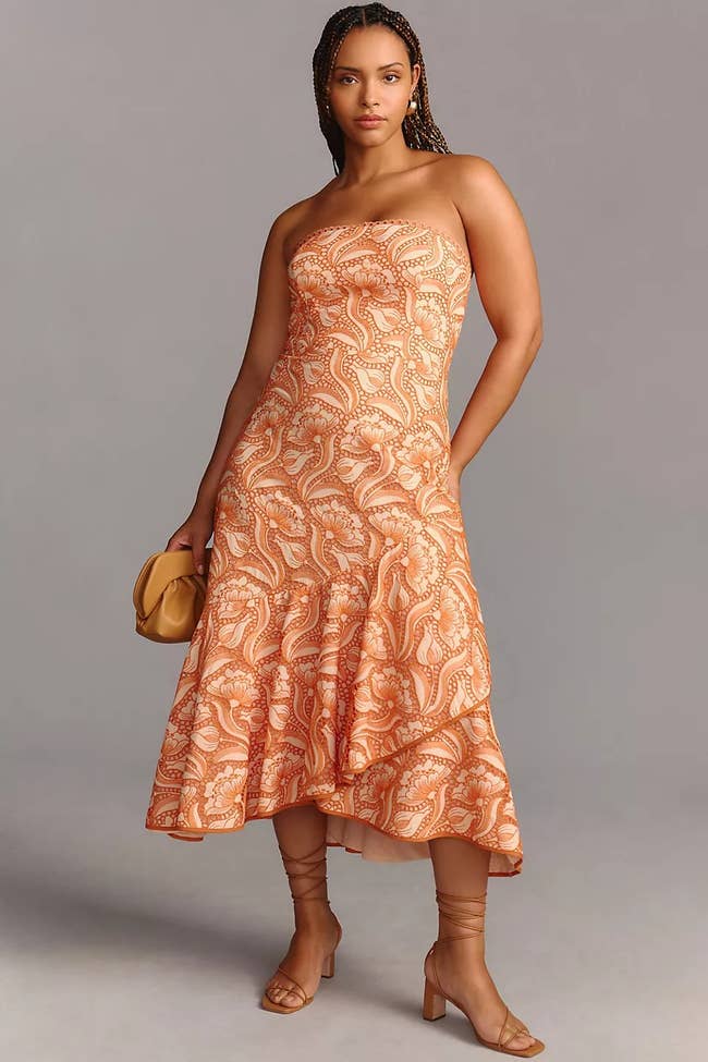 A model posing in the orange lace gown