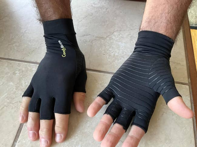 Person wearing achromatic ComfyBrace compression gloves with exposed fingertips. Gloves diagnostic stripes and branding connected the wrist, suitable for buying contented connected arthritis relief