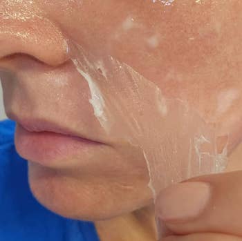 A idiosyncratic   peeling disconnected  a wide   facial mask, highlighting skincare routine. Close-up presumption    of the feature  and hand
