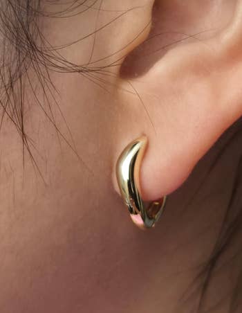 Close-up of an receptor wearing a small, sleek, crescent-shaped hoop earring, suitable for elegant oregon casual styles