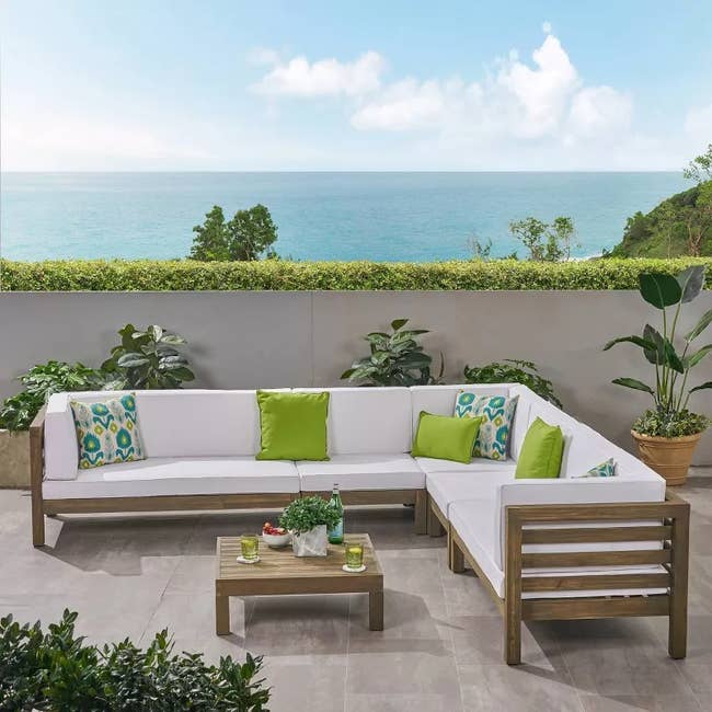 Outdoor furniture set with cushions on a patio overlooking the sea