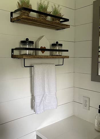 Reviewer image of products in brown and black hung on white wall with white towel on towel bar