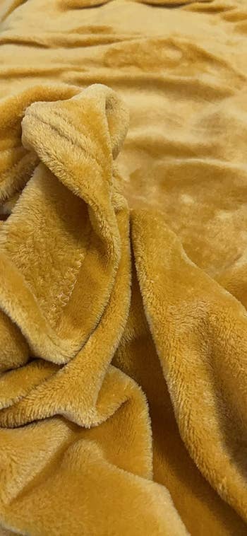 a close up of a reviewer's gold blanket showing how soft it is