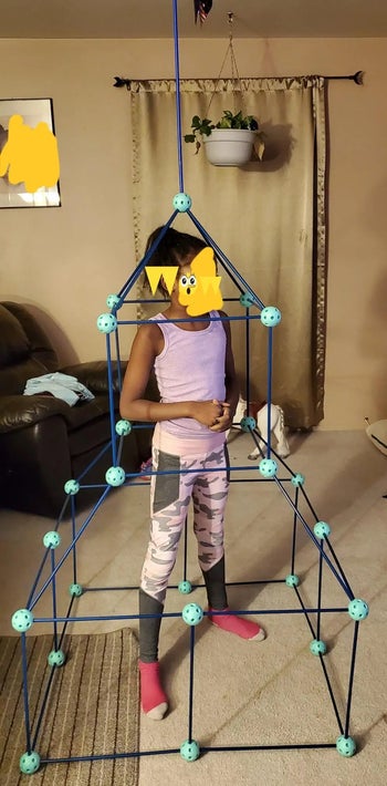 reviewer photo of their child standing inside of a fort