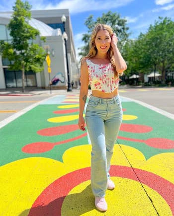 Reviewer in a floral top and jeans standing on a painted street for a casual, spring look