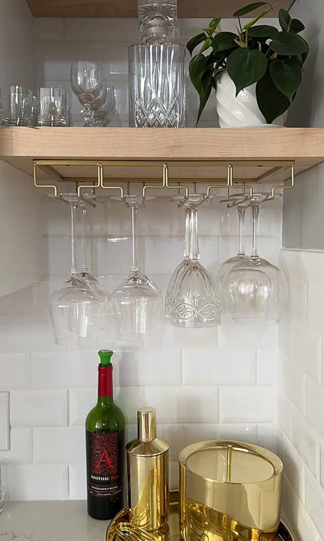Reviewer pic of the wine glass rack attached to the bottom of a cabinet with three rows of classes hanging from it