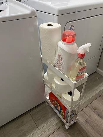 a thin rolling cart in between a washer and dryer