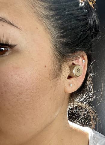 reviewer wearing the rose gold earbud in their ear