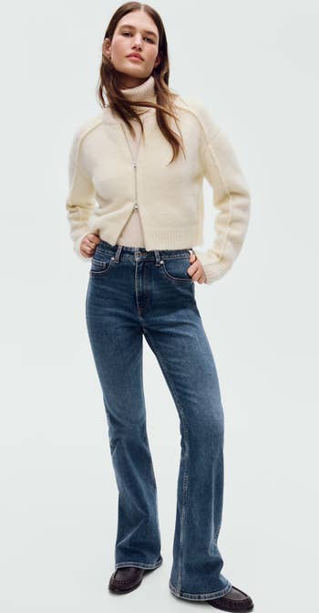 Person wearing a cozy turtleneck sweater and flared jeans, posing stylishly