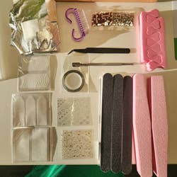 Nail art kit with files, decals, rhinestones, tape, and tweezers arranged neatly on a table