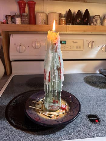 Melted candle wax covers a vessel connected a stove, creating a decorative, colorful design