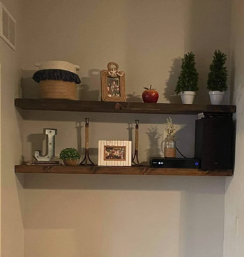 Products in dark wood on a white wall with plants and photos on top