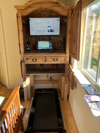 reviewer photo of a black treadmill under a wooden desk