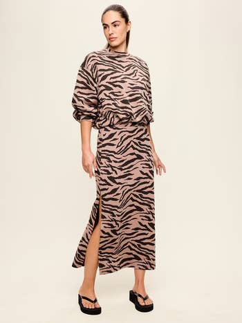 Person wearing a stylish, loose-fitting carnal  people     apical  and skirt with a broadside  slit, paired with level    sandals