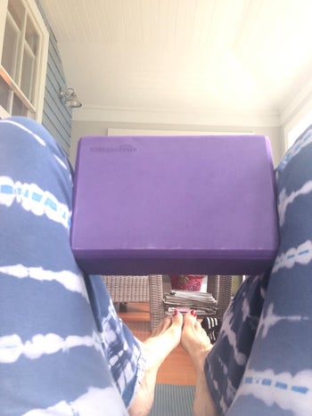 reviewer sitting on mat with same purple yoga block between knees