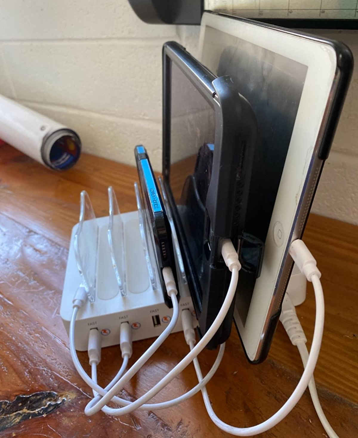 a reviewer photo of the charging station charging a phone and two tablets with empty slots to spare 