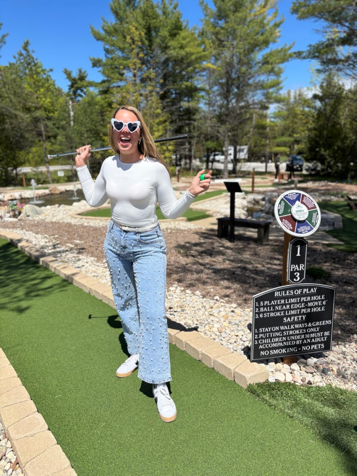 Person successful  high-waist jeans and long-sleeve apical  playfully poses connected  mini-golf people   