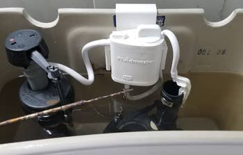 reviewer image of flush 'n sparkle kit in water tank of toilet