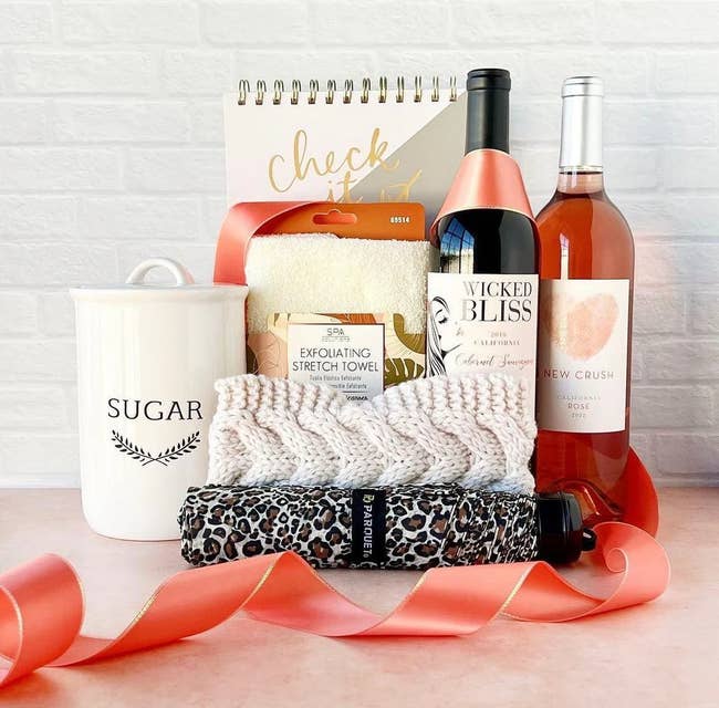 Gift basket with various items, including a planner, bath towel, and bottle of wine, ideal for a personal treat or present
