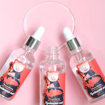 three bottles of the serum with packaging with illustration of a pig stirring a cauldron