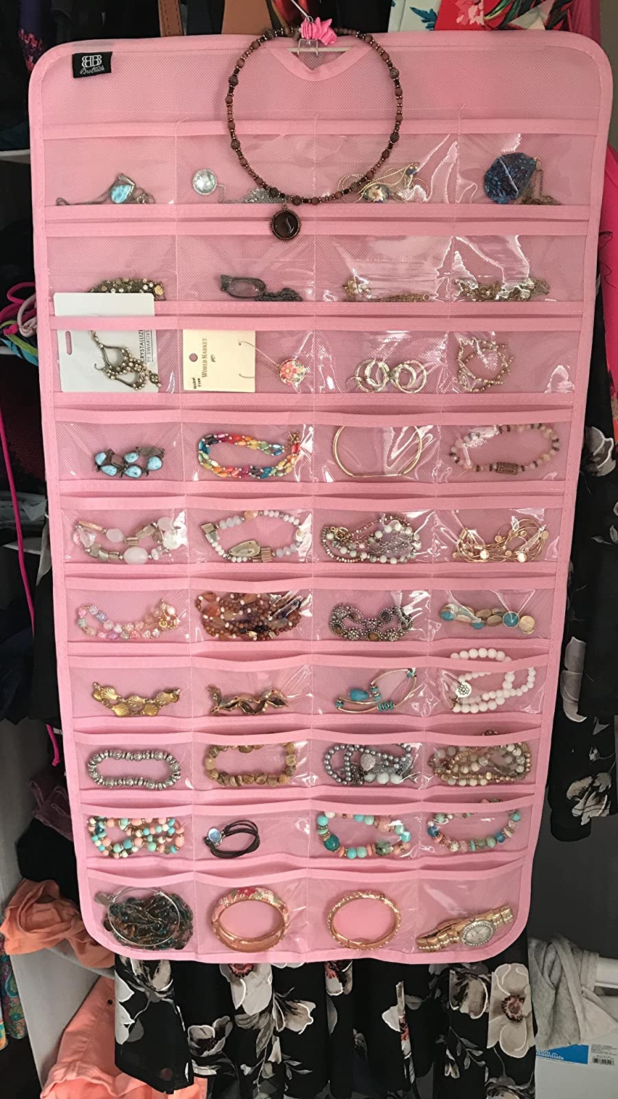 reviewer's pink hanging jewelry organizer hanging up in a closet