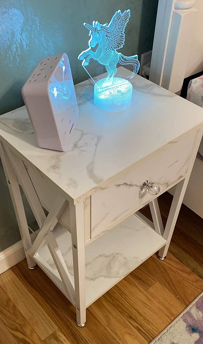 reviewer photo of white marble design nightstand with lightup unicorn lamp
