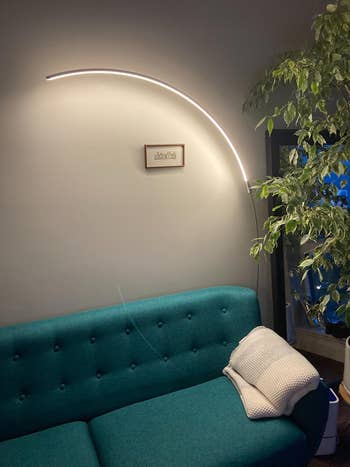 reviewer's curved arc lamp over a teal couch