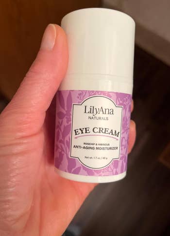 Hand holding LilyAna Naturals Eye Cream container