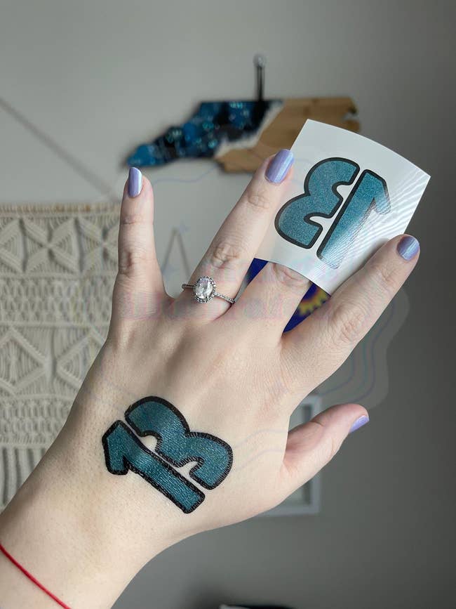 model with teal 13 temporary tattoo on back of hand