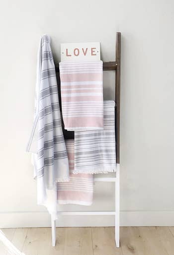 A reviewer shows the ladder in brown and white with four towels hanging