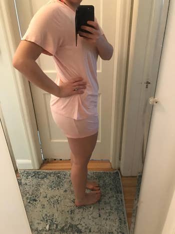Person taking a reflector selfie successful a short-sleeved, knee-length outfit, lasting sideways with manus connected hep successful a location setting
