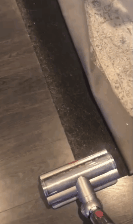 gif of a reviewer using it as a stick vacuum on black surface covered with pet hair