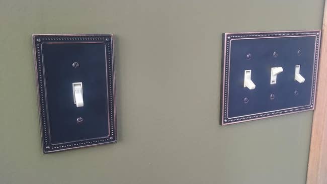 reviewer image of two light switches with the copper and brass switch plate covers