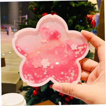 A pink flower shaped coaster with floating glitter pieces inside 