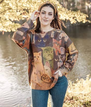 model in the graphic sweater with grumpy looking cats printed all over it