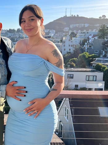 Person in a blue dress holding their baby bump