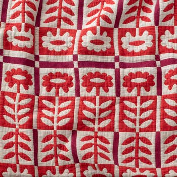 Quilt with a geometric floral signifier   featuring stylized flowers and leaves arranged successful  a grid