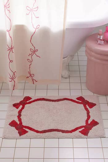 Bathroom setting with a floral shower curtain and a matching bath mat on tiled floor