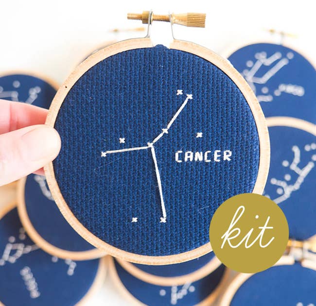 person holding completed cancer constellation cross stitch 