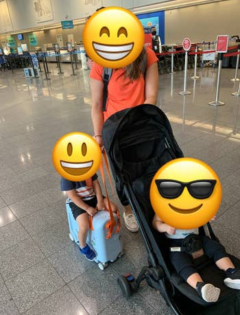 a child sitting on the wheely suitcase with an adult model pulling them next to it and another child in a stroller
