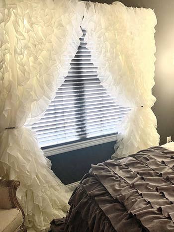 reviewer's white ruffle curtains on their bedroom window 