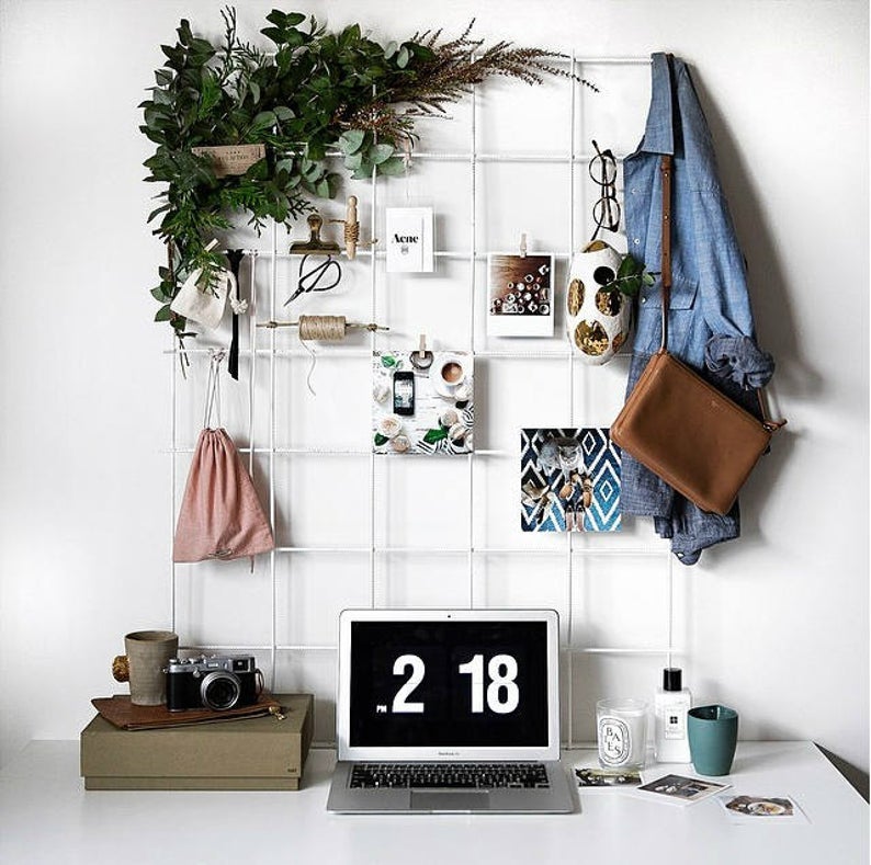 white wire wall grid above a desk with pictures and accessories hanging from it