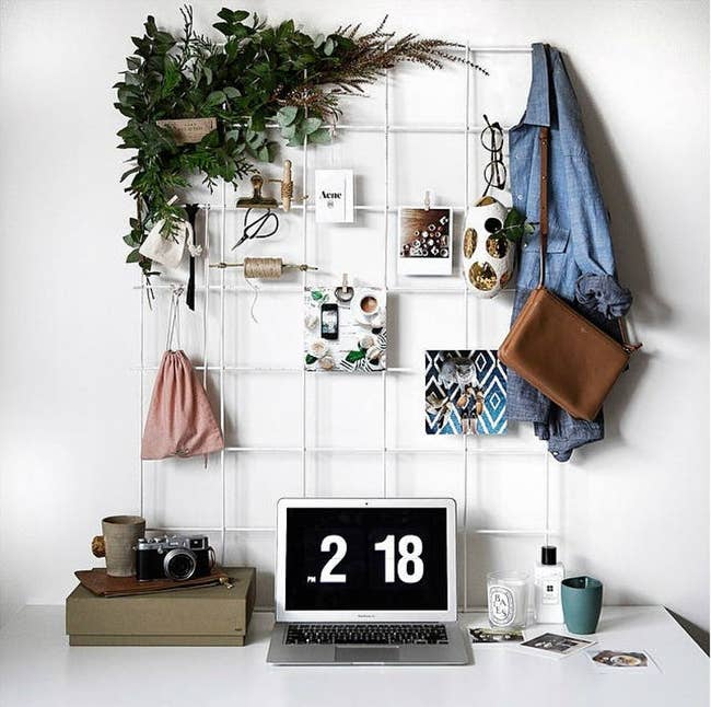 white wire wall grid above a desk with pictures and accessories hanging from it 