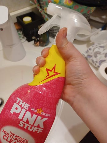 Reviewer holding a pink spray bottle 