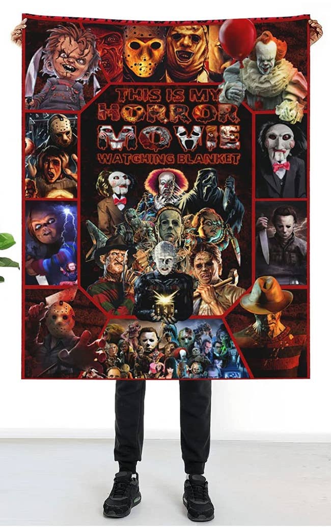 person holding up blanket with iconic horror characters bordering the words this is my horror movie watching blanket 