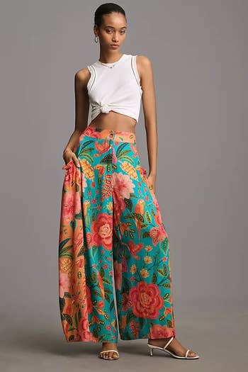 model in white crop top and floral wide-leg pants standing with one hand on hip