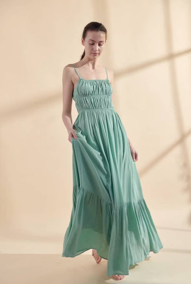 Model in a pale green tiered maxi dress double cinched at the waist 