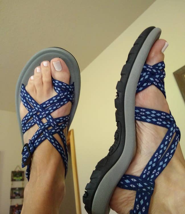 Person wearing blue patterned strappy sandals, showcasing the design for a shopping article